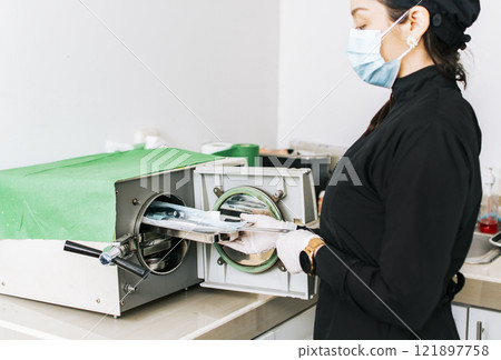 Dentist with a dental sterilizer, A dentist sterilizing his tools, A dentist with a dental autoclave, Close up of a dentist with a steam sterilizer Dentist with a dental sterilizer, A dentist sterilizing his tools, A dentist with a dental autoclave, Close up of a dentist with a steam sterilizer 121897758