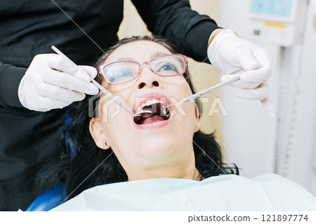 Female dentist checking a patient, close up of dentist with patient, dentist performing root canal on patient, dentist performing dental checkup Female dentist checking a patient, close up of dentist with patient, dentist performing root canal on patient, dentist performing dental checkup 121897774