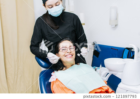 Dentist examining mouth to smiling patient, Female dentist doing root canal to female patient, Female dentist with lying patient, Dentist performing stomatology Dentist examining mouth to smiling patient, Female dentist doing root canal to female patient, Female dentist with lying patient, Dentist performing stomatology 121897793