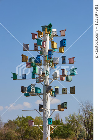 A Colorful Birdhouse Structure Set Beautifully Against a Clear Blue Sky Above It 121897981
