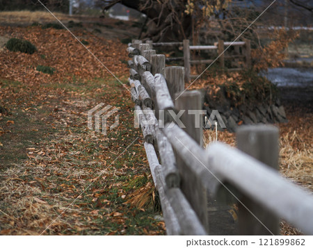 A nostalgic photo of a wooden railing in a barren winter landscape 121899862