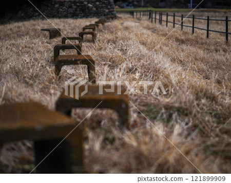 A nostalgic landscape photo of benches and iron fences lined up in a winter-dead grassland 121899909