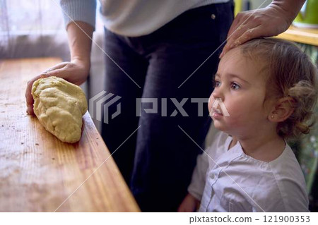 a     mother and teenage daughter are cooking cookies together in the kitchen 121900353