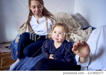 family with toddler and teenager playing games, laughing, clapping and celebrating a small family party 121900377