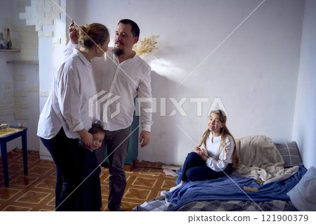 family with toddler and teenager playing games, laughing, clapping and celebrating a small family party 121900379