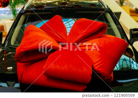 a big red bow on a new car. gift wrapping at a car dealership a big red bow on a new car. gift wrapping at a car dealership 121900509