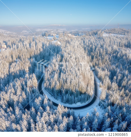 Aerial view on the curvy road and forest at the winter time. Forest covered in snow. Aerial view on the curvy road and forest at the winter time. Forest covered in snow. 121900865