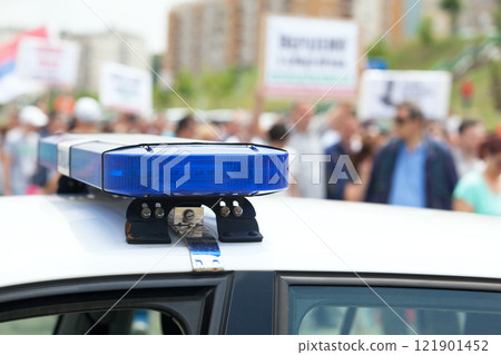 Police car flashing lights in focus, blurred protesters in the background Police car flashing lights in focus, blurred protesters in the background 121901452