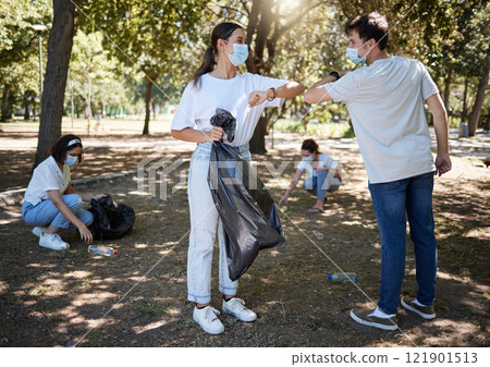 Covid, cleaning and volunteers wearing masks while cleaning a community park and saying thank you with a elbow gesture. Social disdancing between friends doing a cleanup outdoors during a pandemic Covid, cleaning and volunteers wearing masks while cleaning a community park and saying thank you with a elbow gesture. Social disdancing between friends doing a cleanup outdoors during a pandemic 121901513