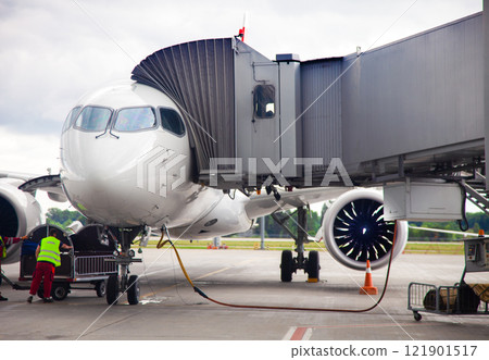 Refueling the aircraft at the airport before departure. The white plane is on the platform, the passengers sit through the boarding bridge. Handling service Refueling the aircraft at the airport before departure. The white plane is on the platform, the passengers sit through the boarding bridge. Handling service 121901517