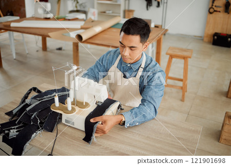 Creative fashion designer or seamstress tailor working on sewing trendy and stylish clothing garment in design studio workshop. Young male dressmaker working on fabric material with machine stitch 121901698
