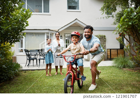 Boy on bicycle learning with proud dad and happy family in their home garden outdoors. Smiling father teaching fun skill, helping and supporting his excited young son to ride, cycle and pedal a bike Boy on bicycle learning with proud dad and happy family in their home garden outdoors. Smiling father teaching fun skill, helping and supporting his excited young son to ride, cycle and pedal a bike 121901707