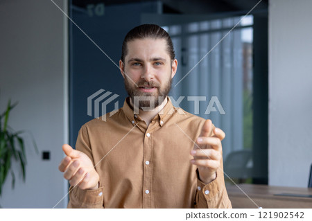 A professional-looking man gestures expressively during a presentation or collaborative meeting in a modern office setting. 121902542