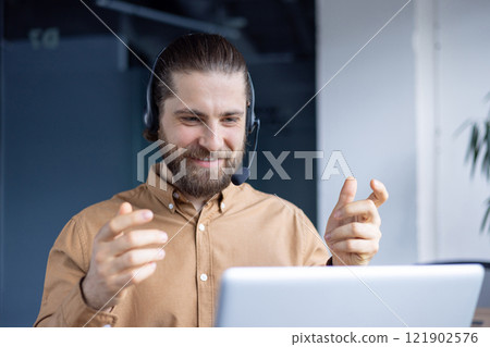 A cheerful man wearing headphones and gesturing during an engaging online video conference. 121902576