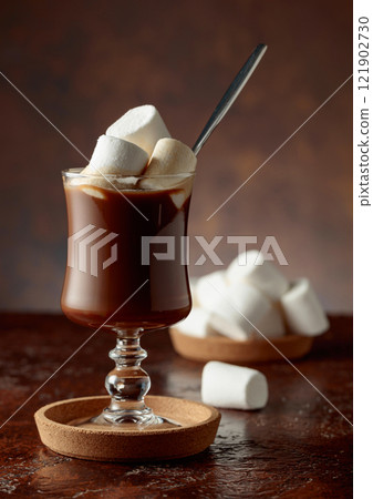 Hot chocolate with marshmallows in a glass mug on a old brown table. 121902730