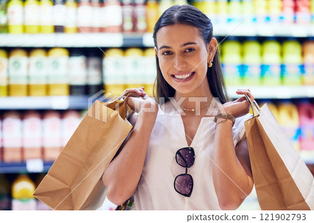 Portrait of satisfied woman shopping for groceries, smiling as she buys at the supermarket. Cheerful, young and shopaholic caucasian woman purchasing in store, buying food and products for sale. 121902793