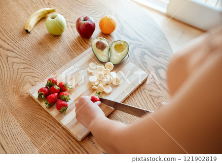 Health, diet and healthy woman cutting fruit to make a smoothie with nutrition for an organic meal at home. Closeup of caucasian female hands chopping fresh produce for a health in a kitchen. 121902819