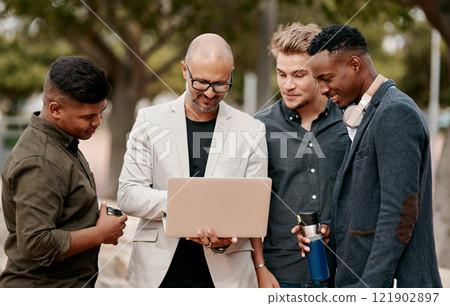 A team leader coaching his staff outdoors, standing and using a laptop. A group of male designers working on a start up project, looking at content on a computer outside, teamwork in the open air. 121902897