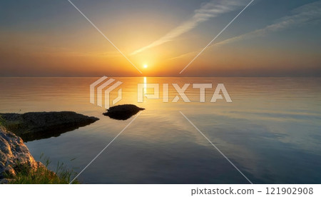 Gentle waves reflecting the golden hues of a breathtaking sunrise over a tranquil ocean. 121902908