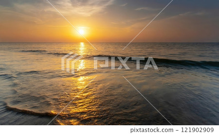 Gentle waves reflecting the golden hues of a breathtaking sunrise over a tranquil ocean. 121902909