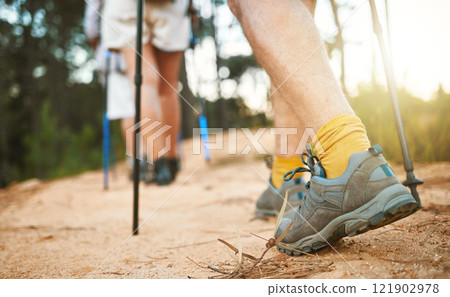 Feet or shoes walking, trekking and hiking on a trail up a mountain with sticks and poles. Closeup of group of adventurous hikers or friends exploring rugged path on a mountain in nature 121902978