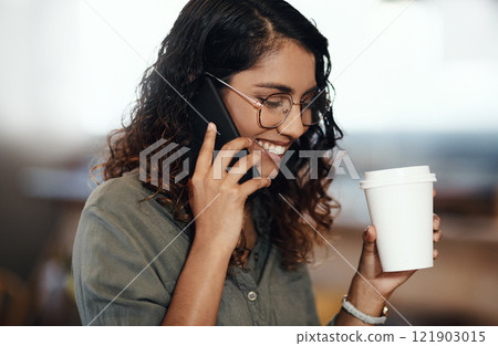 Young woman talking on her phone, drinking coffee, and smiling in cafe shop. Lady wearing glasses, using technology to network and connect while enjoying a break from work. 121903015