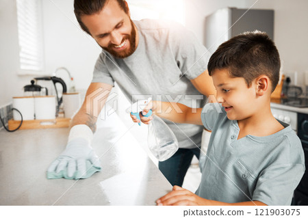 Father teaching young son cleaning chores in the family home having fun and bonding together. Smiling and loving father helping, washing and wiping kitchen counter with his little boy indoors 121903075