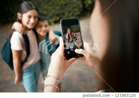 Children first day of school and mother taking photos with a phone of her cute kids. Closeup of screen picture of brother and sister embracing while posing for their mom outside in the morning Children first day of school and mother taking photos with a phone of her cute kids. Closeup of screen picture of brother and sister embracing while posing for their mom outside in the morning 121903120