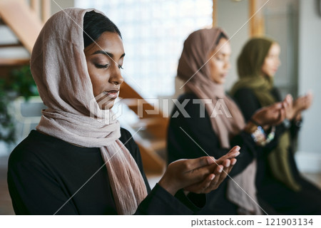 Praying, muslim and young women group practicing arabic, holy and islamic religion indoors. Females wearing a hijab while kneeling to practice a quiet, spiritual and worship prayer inside in silence 121903134