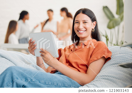 Relaxed, happy and relaxing digital marketing agency employee on a break browsing the internet on a tablet. Portrait of a smiling, young and excited female worker searching for social media trends 121903143