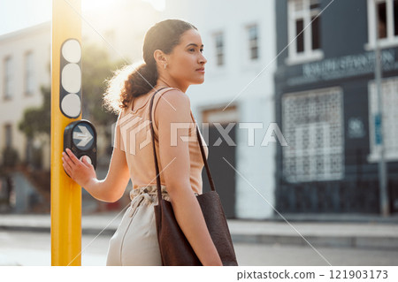 Attractive female pedestrian ready to cross the street, waiting for green light and pressing the button at a crossing Young city woman on a morning walk to work, standing and looking out for traffic. 121903173