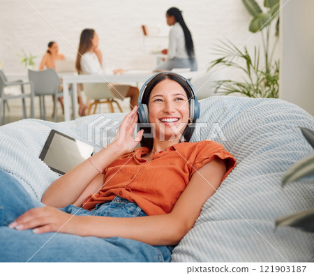 Listening to music, headphones and songs from a tablet playlist for creative relaxing, enjoying and lying on office bean bag. Smiling, happy and motivated business woman on break and feeling inspired Listening to music, headphones and songs from a tablet playlist for creative relaxing, enjoying and lying on office bean bag. Smiling, happy and motivated business woman on break and feeling inspired 121903187