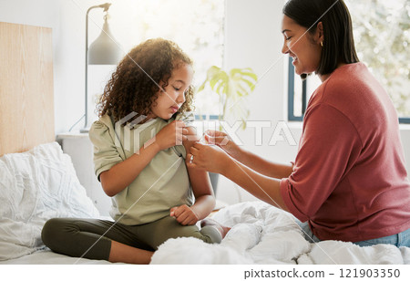 Loving mother comforting her daughter with a bandage in bed, being affectionate and caring at home. Young parent helping her sick child, applying a plaster and bonding, special moments of motherhood 121903350