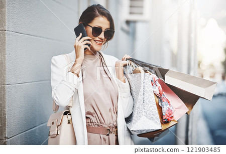 Trendy, stylish and fashionable woman shopping, purchasing and buying clothes in city, town and downtown. Elegant lady talking on phone with gift bags, going on spending spree or doing retail therapy Trendy, stylish and fashionable woman shopping, purchasing and buying clothes in city, town and downtown. Elegant lady talking on phone with gift bags, going on spending spree or doing retail therapy 121903485