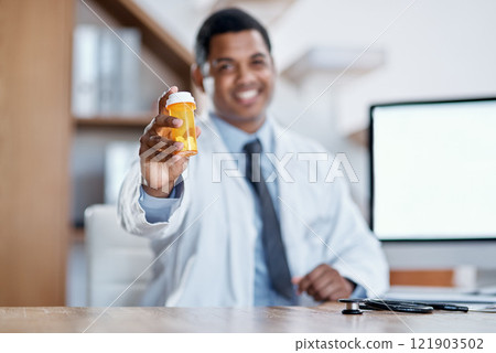 Happy, joyful and friendly male medical doctor offers a bottle of pills to a client with a smile. Smiling, excited and positive healthcare consultant holding antibiotic medicine sitting at desk. 121903502