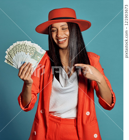 Rich young woman holding cash, competition or lottery winnings pointing looking stylish, elegant and trendy. Happy, excited and celebrating female cheering with income, savings or investment returns 121903673