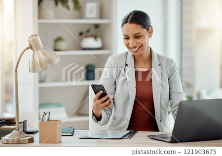 Freelance and remote working business woman checking her phone, reading a message or sending a text in her home office. Motivated, happy and positive female professional sitting at her desk at work 121903675