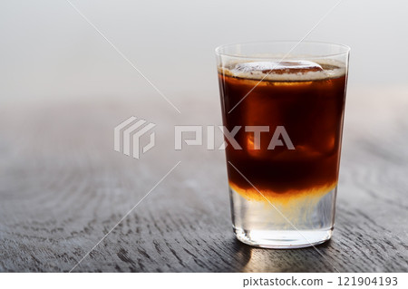 Espresso tonic with clear ice cube in tumbler glass on oak wood table with copy space Espresso tonic with clear ice cube in tumbler glass on oak wood table with copy space 121904193