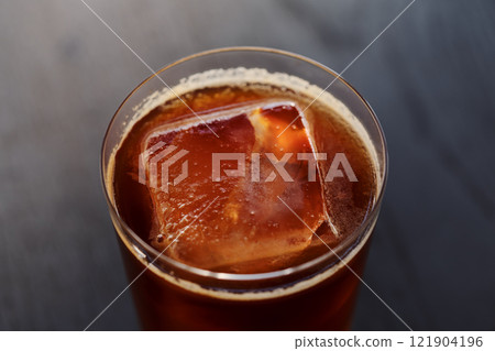 Closeup espresso tonic with clear ice cube in tumbler glass on oak wood table Closeup espresso tonic with clear ice cube in tumbler glass on oak wood table 121904196