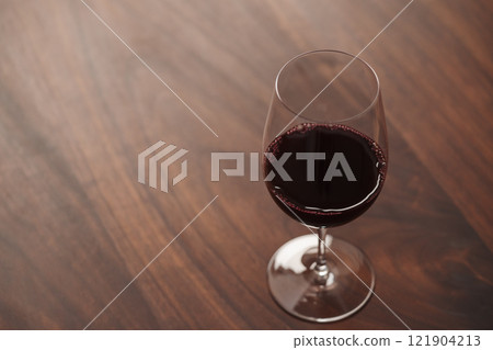 Red wine in wineglass on black walnut table with copy space 121904213