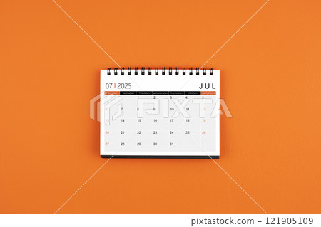July 2025 Monthly desk calendar on orange leather background. July 2025 Monthly desk calendar on orange leather background. 121905109