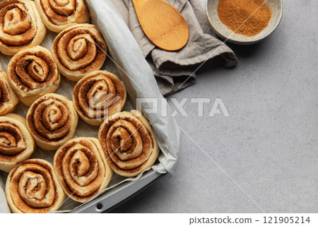 Cinnamon rolls prepared for baking with brown sugar and wooden spoon Cinnamon rolls prepared for baking with brown sugar and wooden spoon 121905214