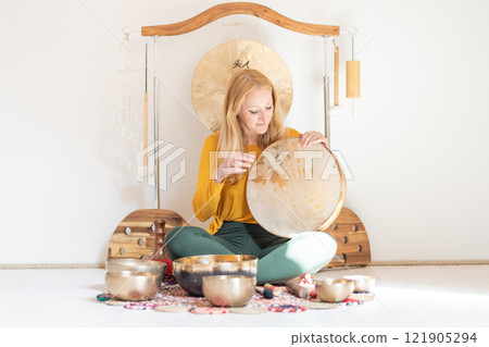 Young cheerful woman performing music therapy session with traditional instruments. Sound meditation, body healing. Seven chakras. Healthcare recreation process 121905294