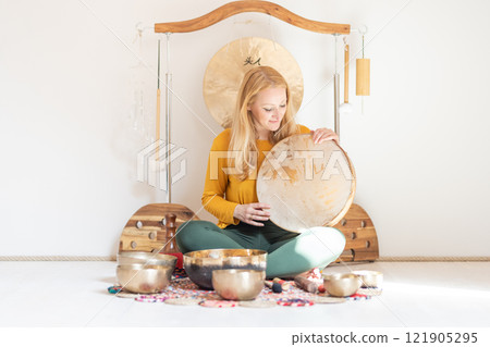 Young cheerful woman performing music therapy session with traditional instruments. Sound meditation, body healing. Seven chakras. Healthcare recreation process 121905295