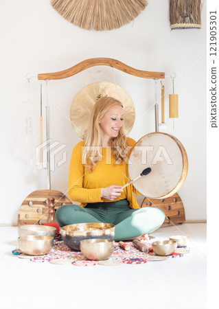 Young cheerful woman performing music therapy session with traditional instruments. Sound meditation, body healing. Seven chakras. Healthcare recreation process 121905301