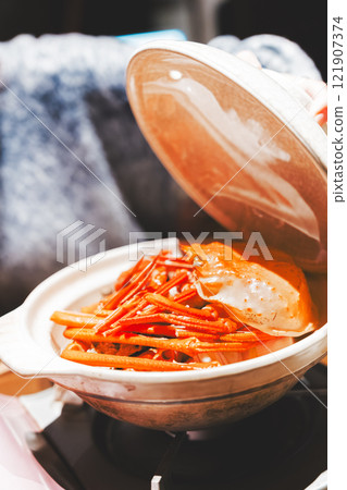 A young woman opening the lid of a crab pot [Photo courtesy of Seafood Izakaya Gyoruko] 121907374