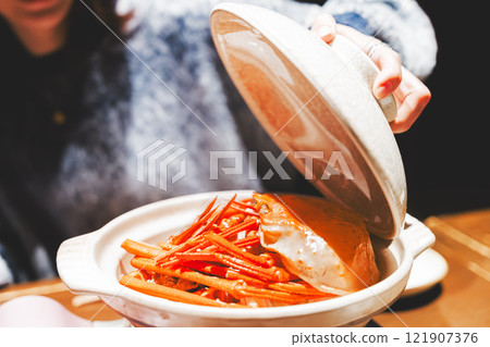 A young woman opening the lid of a crab pot [Photo courtesy of Seafood Izakaya Gyoruko] 121907376
