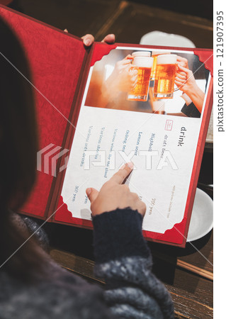 A female customer looks at the menu and makes a selection [Photo courtesy of Seafood Izakaya Gyoruko] 121907395