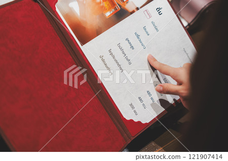 A female customer looks at the menu and makes a selection [Photo courtesy of Seafood Izakaya Gyoruko] 121907414