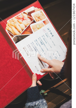 A female customer looks at the menu and makes a selection [Photo courtesy of Seafood Izakaya Gyoruko] 121907434